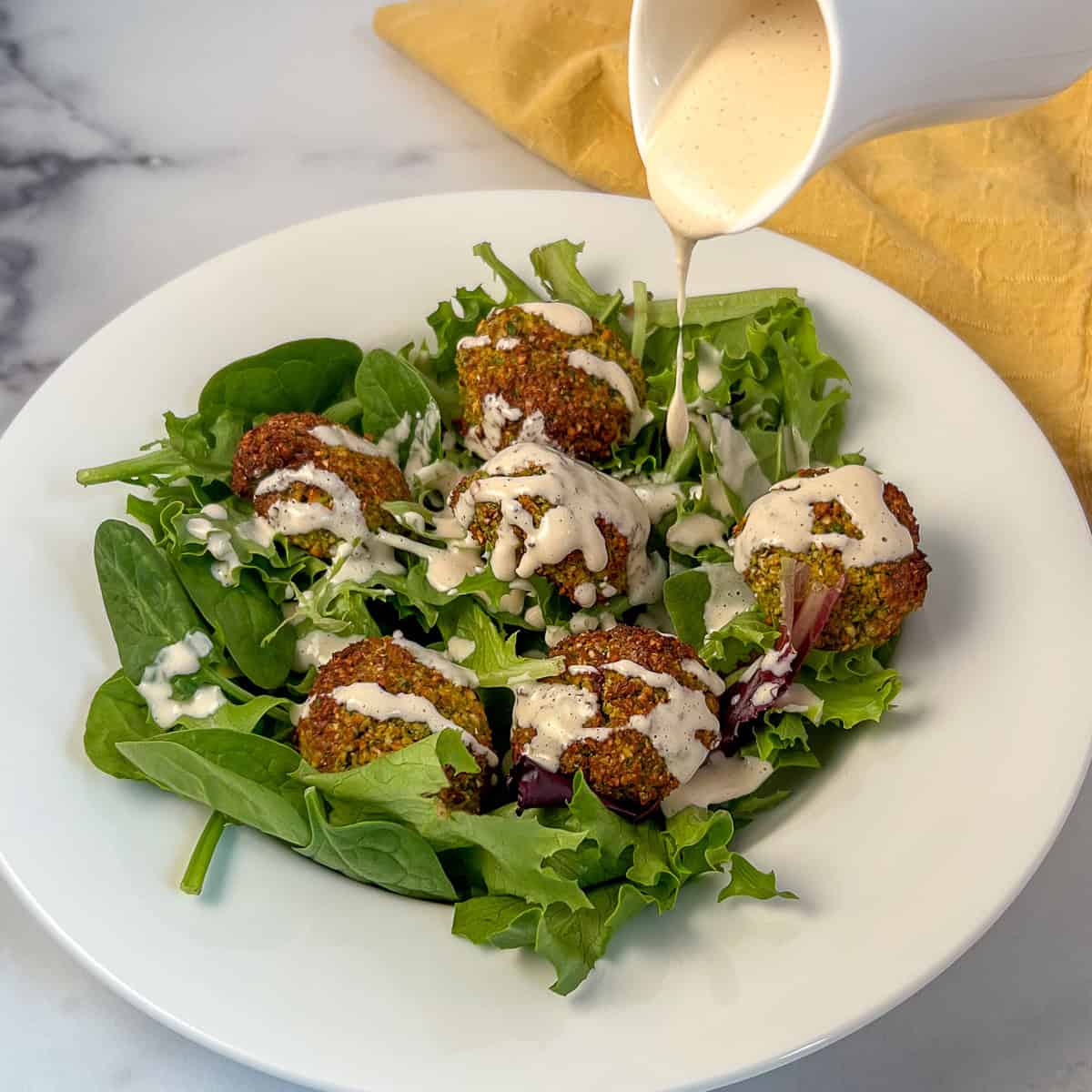 Air fryer falafel on a salad topped with tahini lemon garlic dressing.