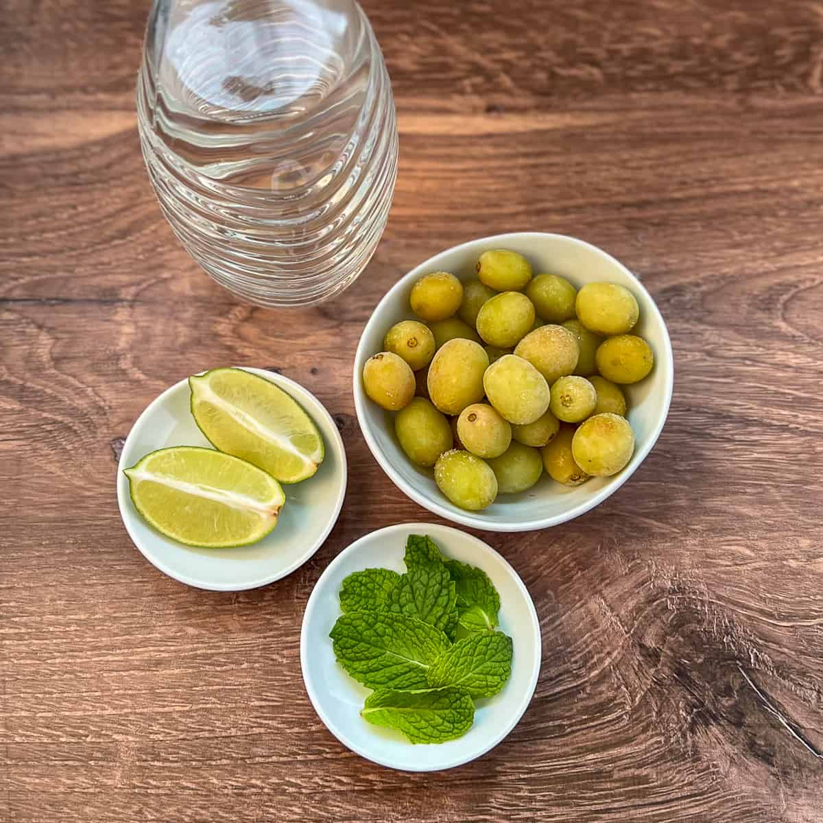 Key ingredients for healthy mojito mocktail: frozen green grapes, fresh mint, fresh lime and sparkling water.