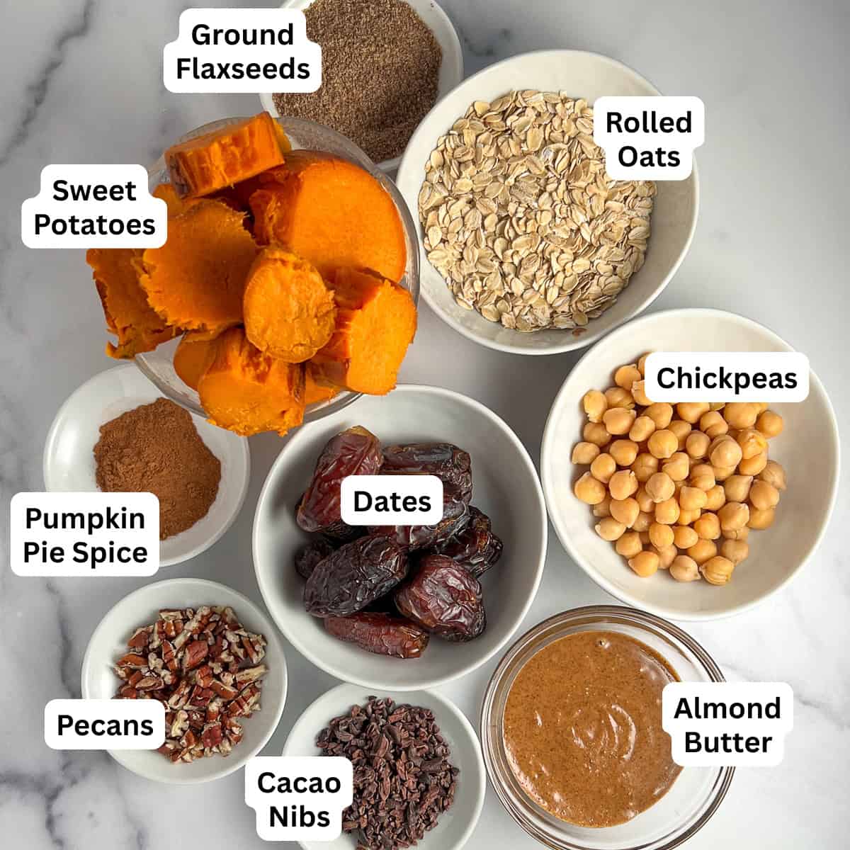 Ingredients used to make the crustless sweet potato pie: baked sweet potatoes, rolled oats, pumpkin pie spice, dates, chickpeas, chopped nuts, almond butter, and cacao nibs.