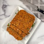 Cooked lentil loaf that's been partially sliced on a plate.