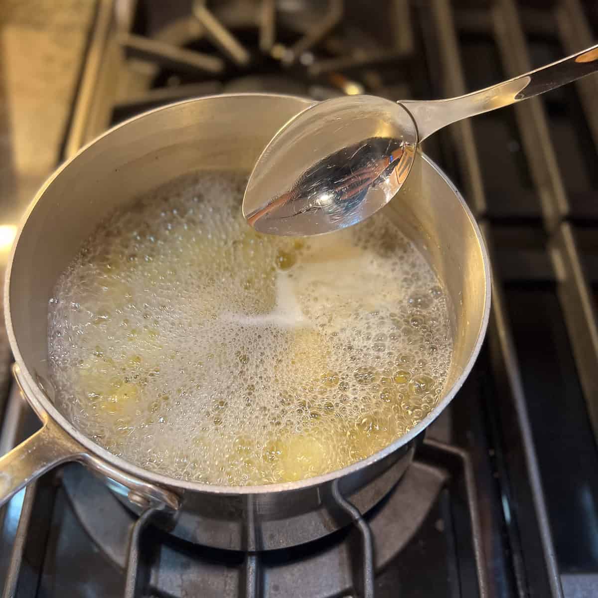 Potatoes and garlic boiling in a pot of water on the stovetop.