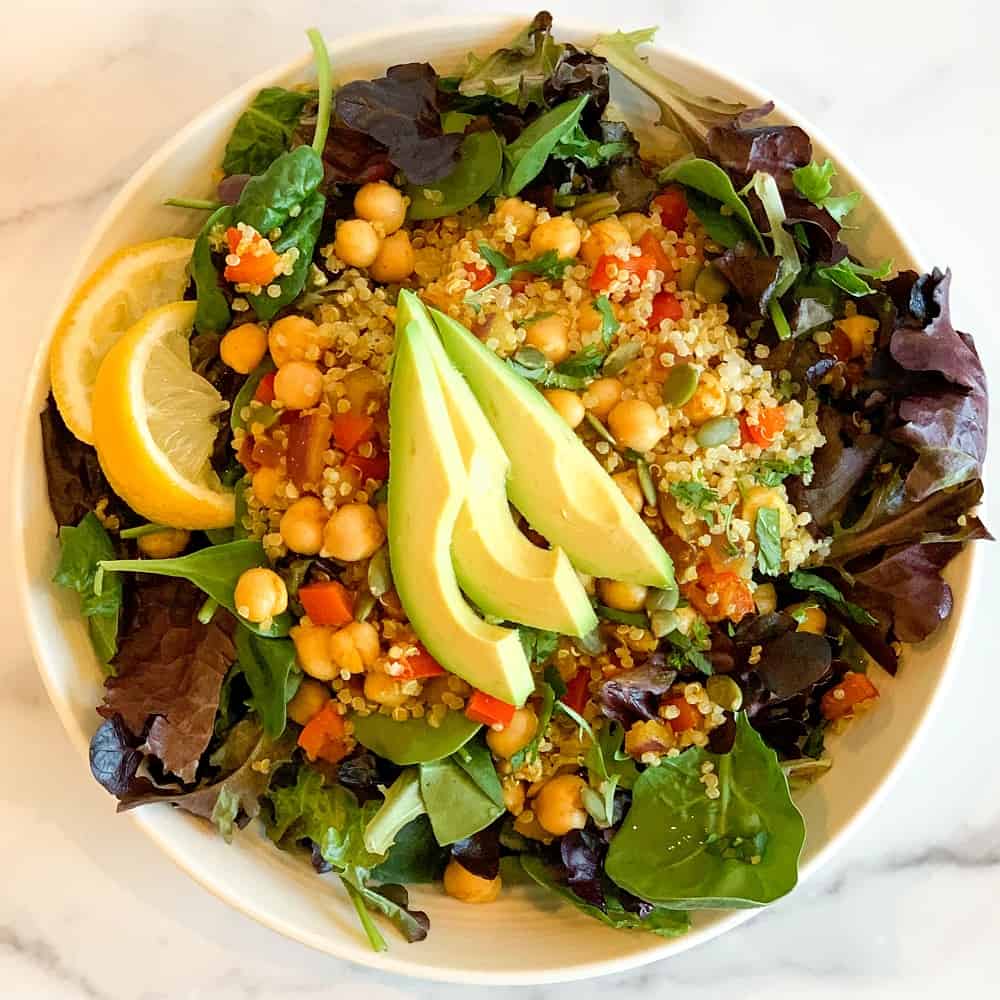 top view close up of curry quinoa chickpea salad with sliced avocado and lemon on the side.