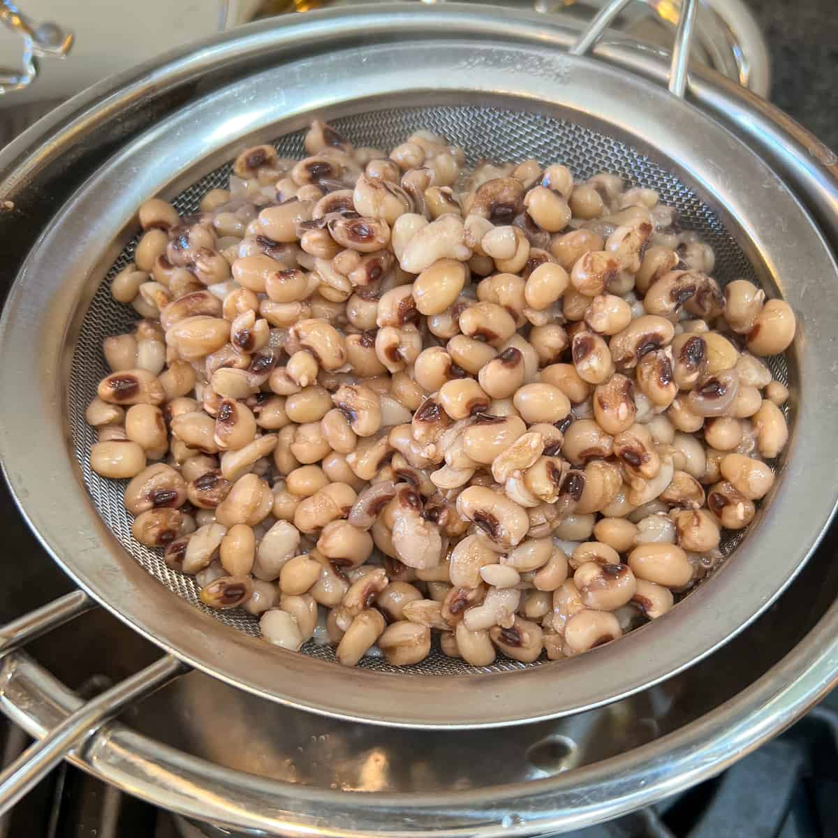 top side view of cooked black eyed peas being strained to remove excess water