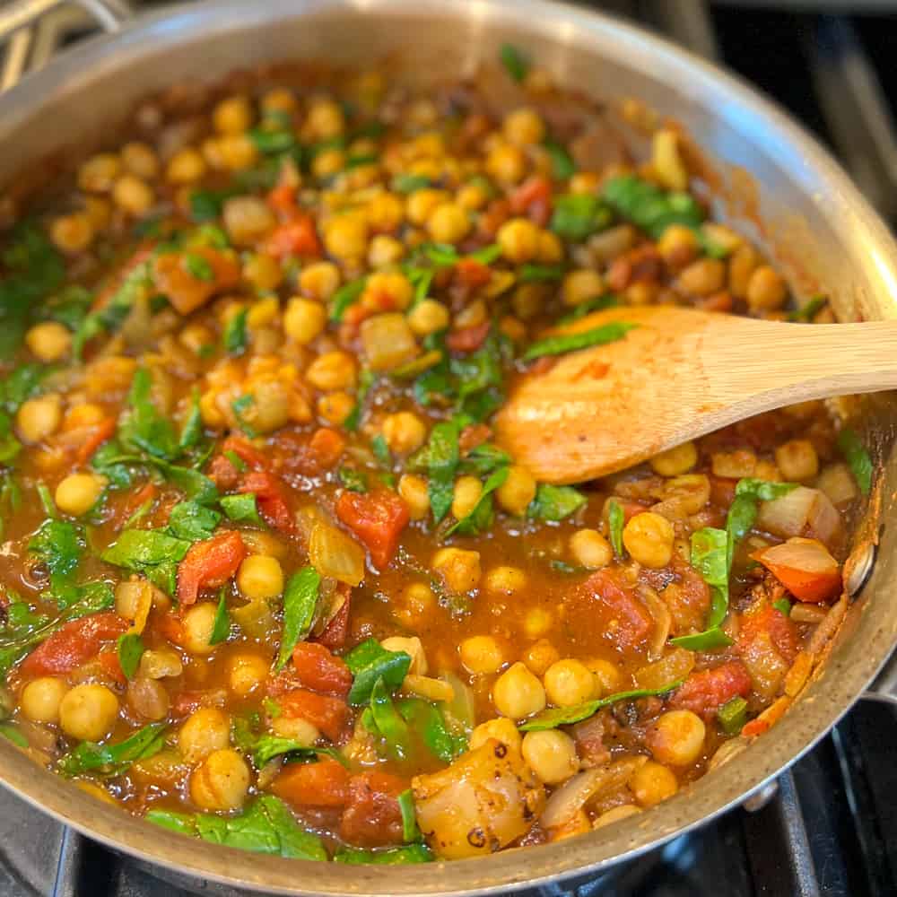 easy vegan chana masala in a sauté pan simmering uncovered on a stovetop