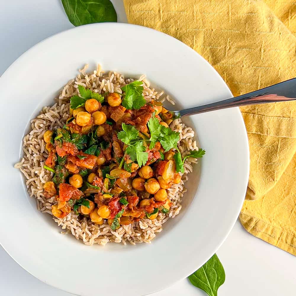 top view close up of easy vegan chana masala over brown basmati rice in a white bowl 