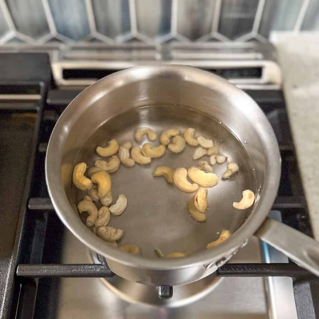Cashews simmering in a pot on the stove.