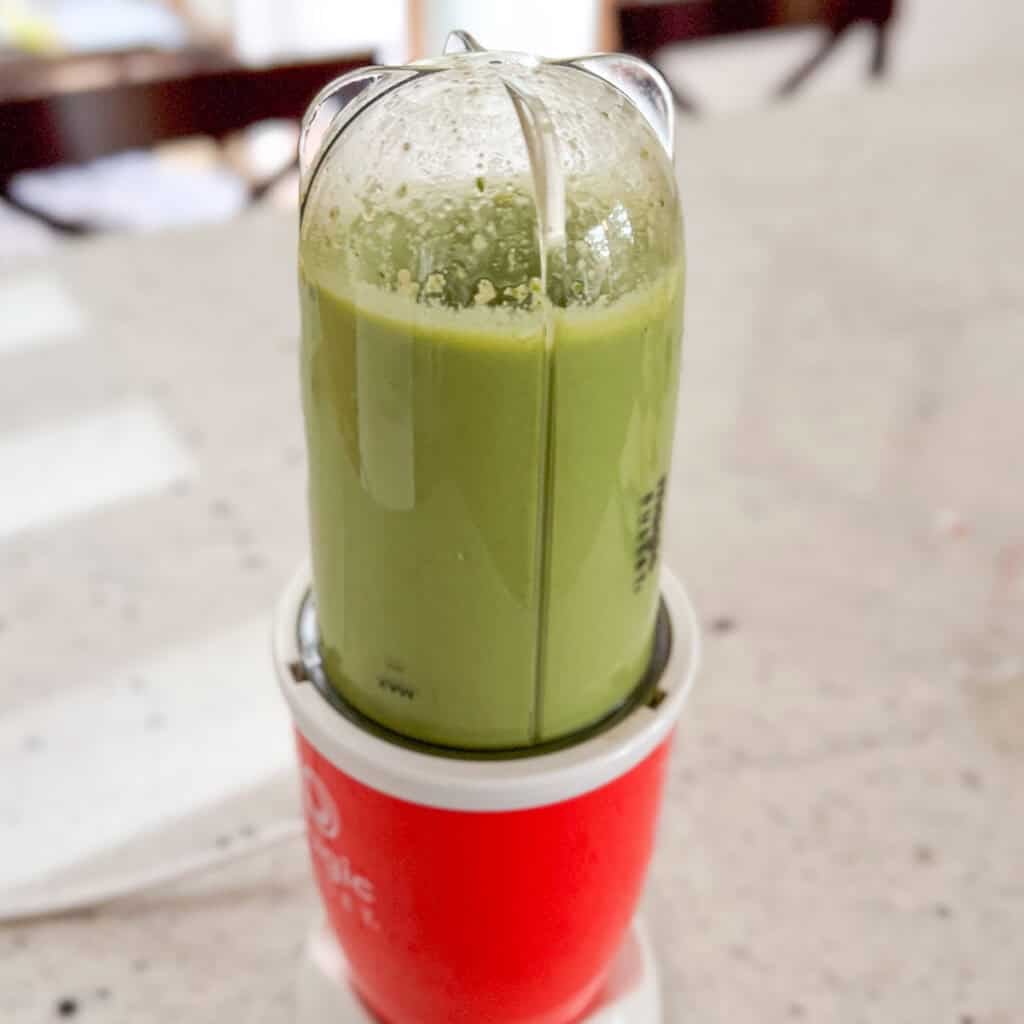 Green goddess dressing being blended in a mini bullet blender.
