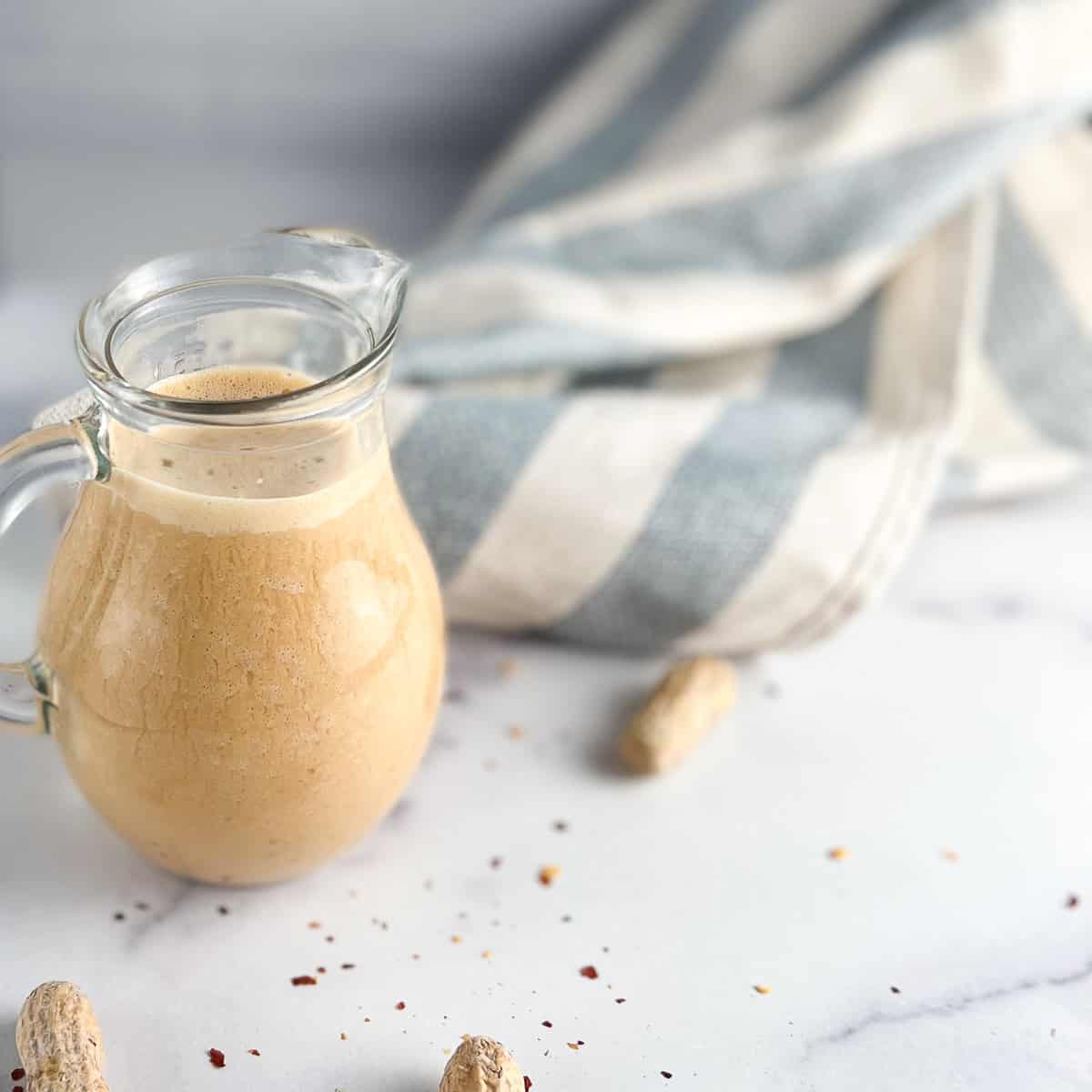 A small pitcher with vegan peanut sauce.