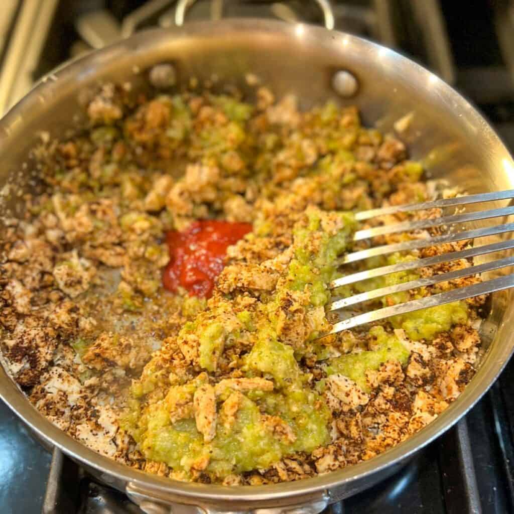 The sauce being incorporated into the tofu sofritas in the skillet.