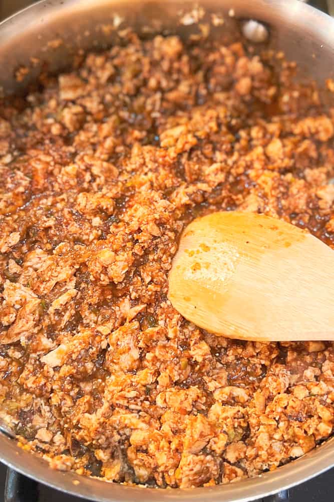 close up of sofritas cooking in a pan with a wooden spoon