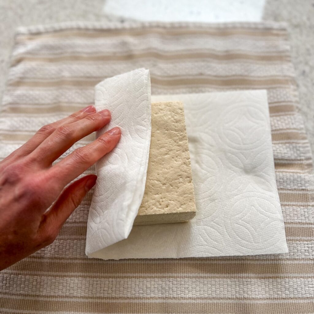 Tofu being pressed to remove excess water.