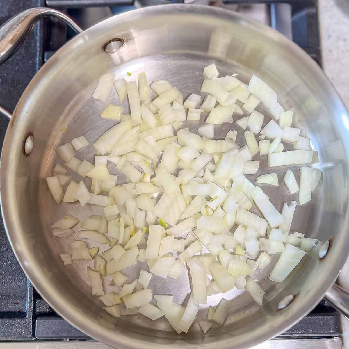 Chopped onion being sautéed in a pan.