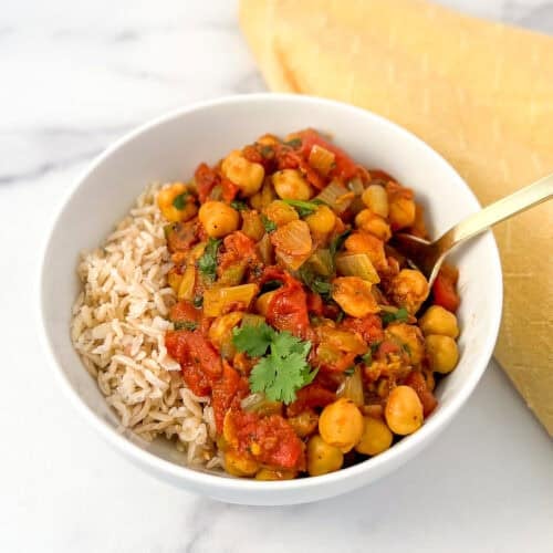 A bowl of vegan chana masala with a side of brown rice.