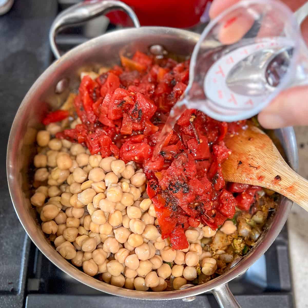 Chickpeas, coconut aminos, tomatoes and water added to the skillet.