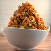 side view close up of a mound of vegan tuna salad made from carrots in a white bowl on wood surface