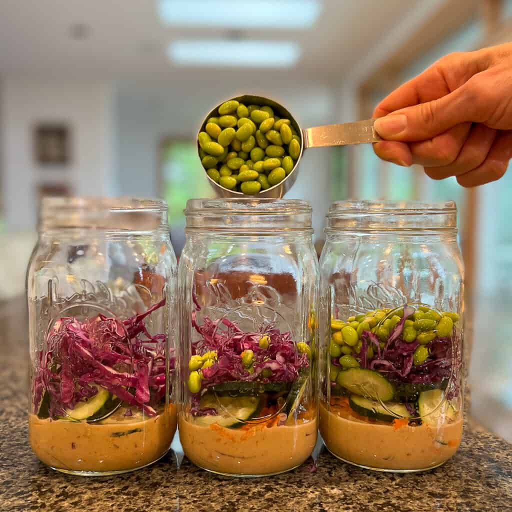 three mason jars with ½ cup edamame being added 