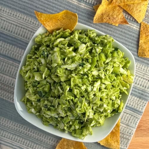 top view close up of green goddess salad in a white bowl with baked tortilla chips