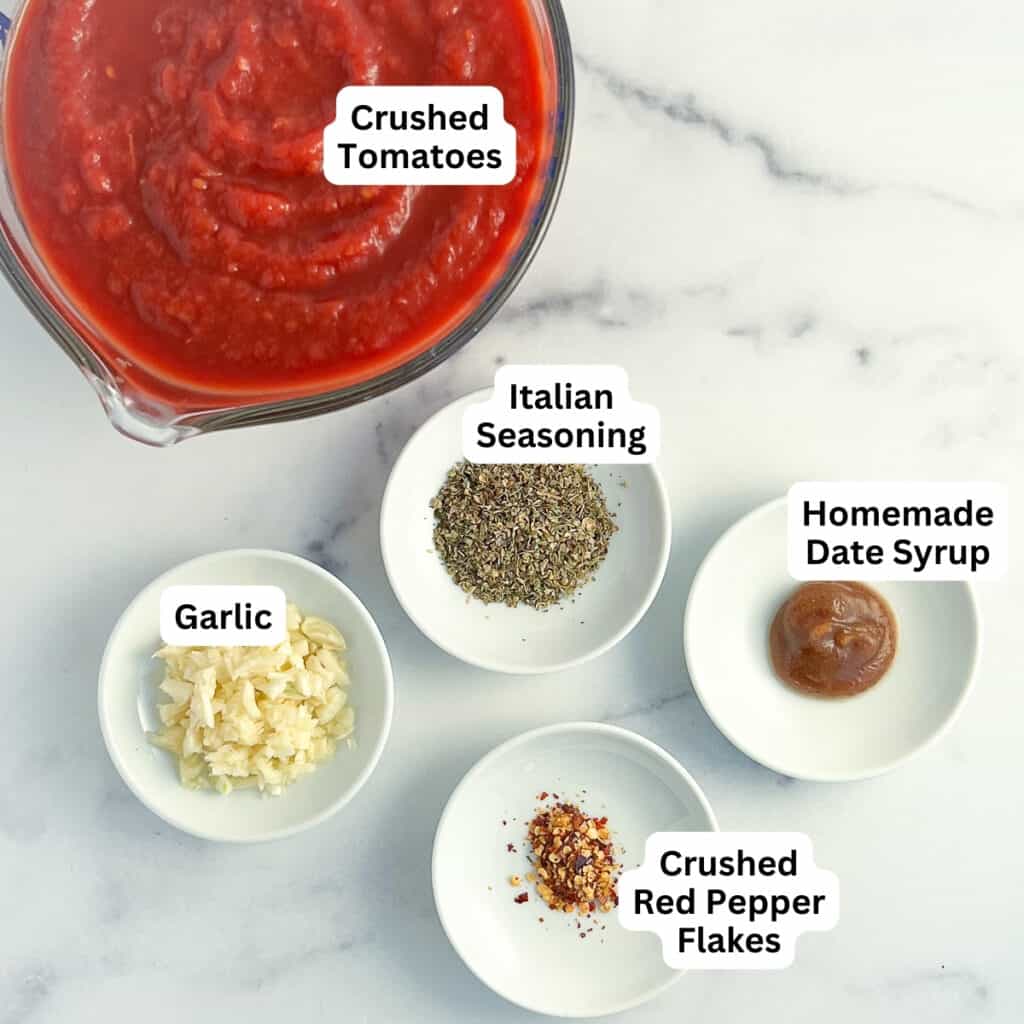 Ingredients for vegan spaghetti sauce: crushed tomatoes, italian seasoning blend, garlic, date syrup and crushed red peppers.