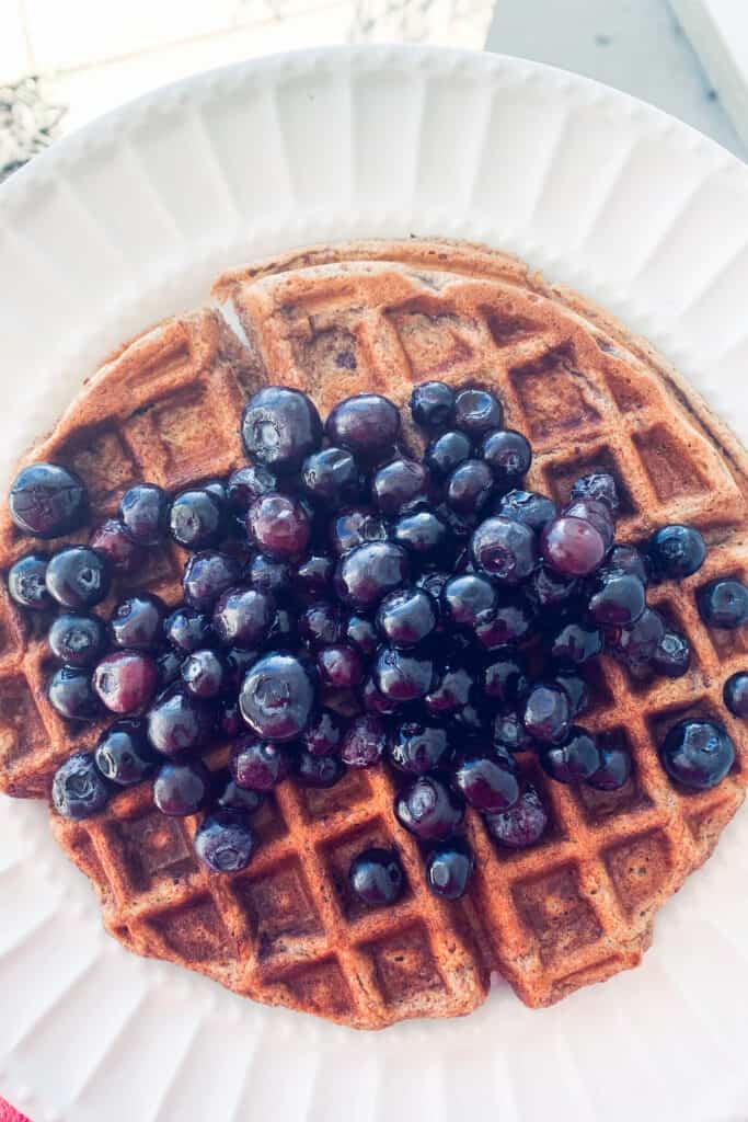 top view of banana oatmeal waffle on a white plate with blueberries on top