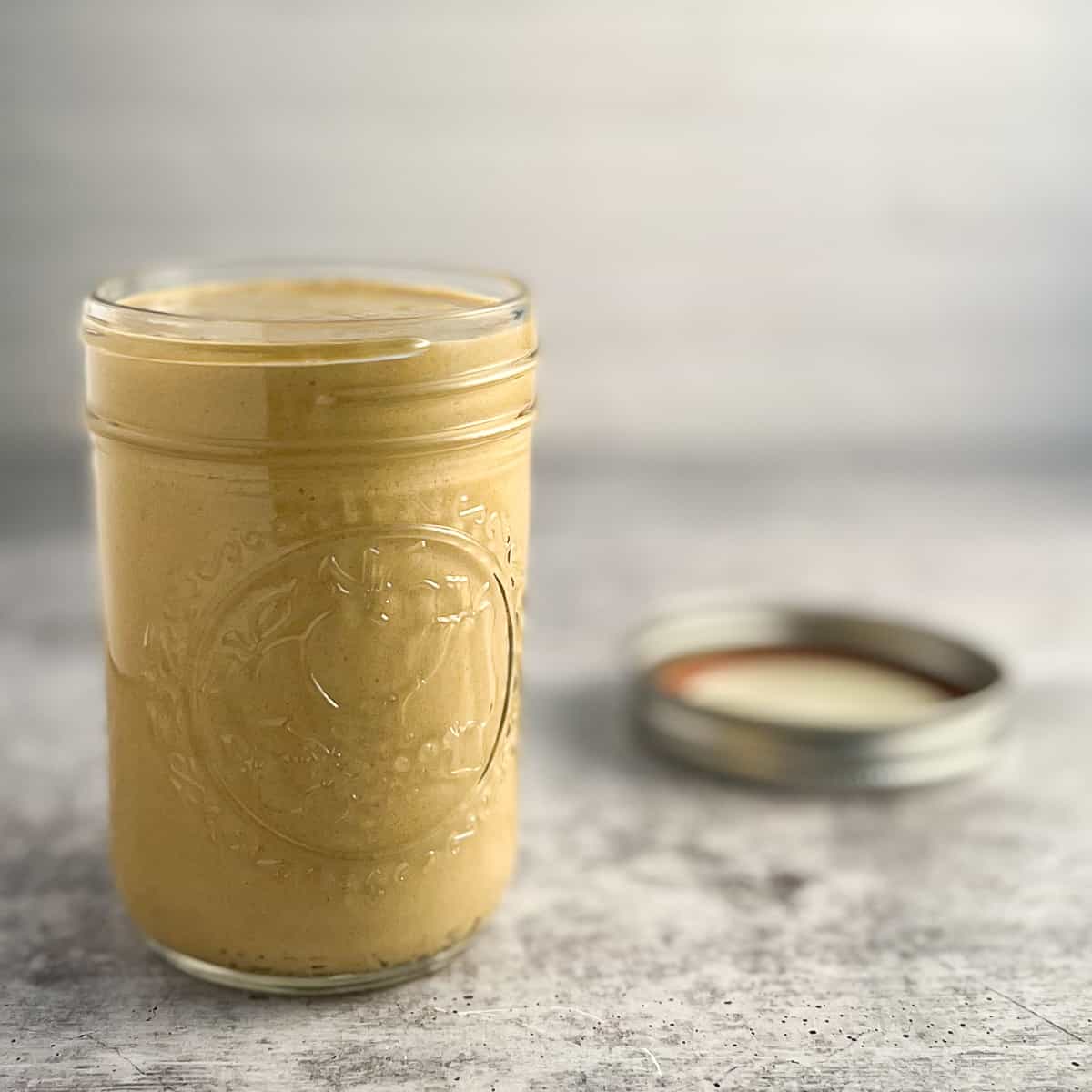 side view of best tahini pasta sauce in a mason jar with lid blurred on the side
