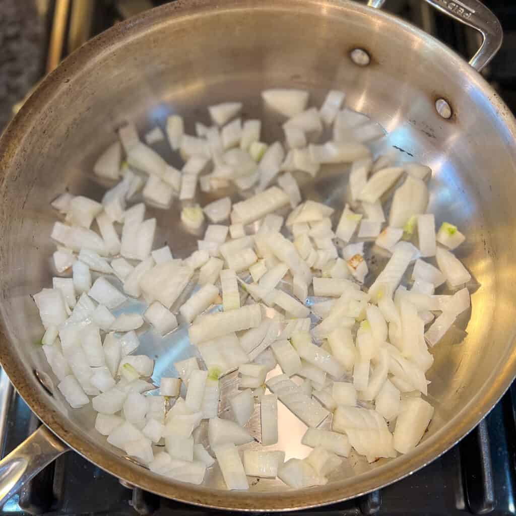 Chopped onions being sautéed in a skillet.