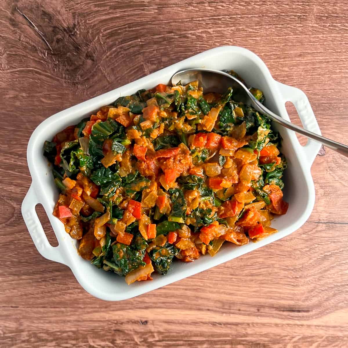 top view of peanut butter greens in a white rectangular casserole dish on wooden surface