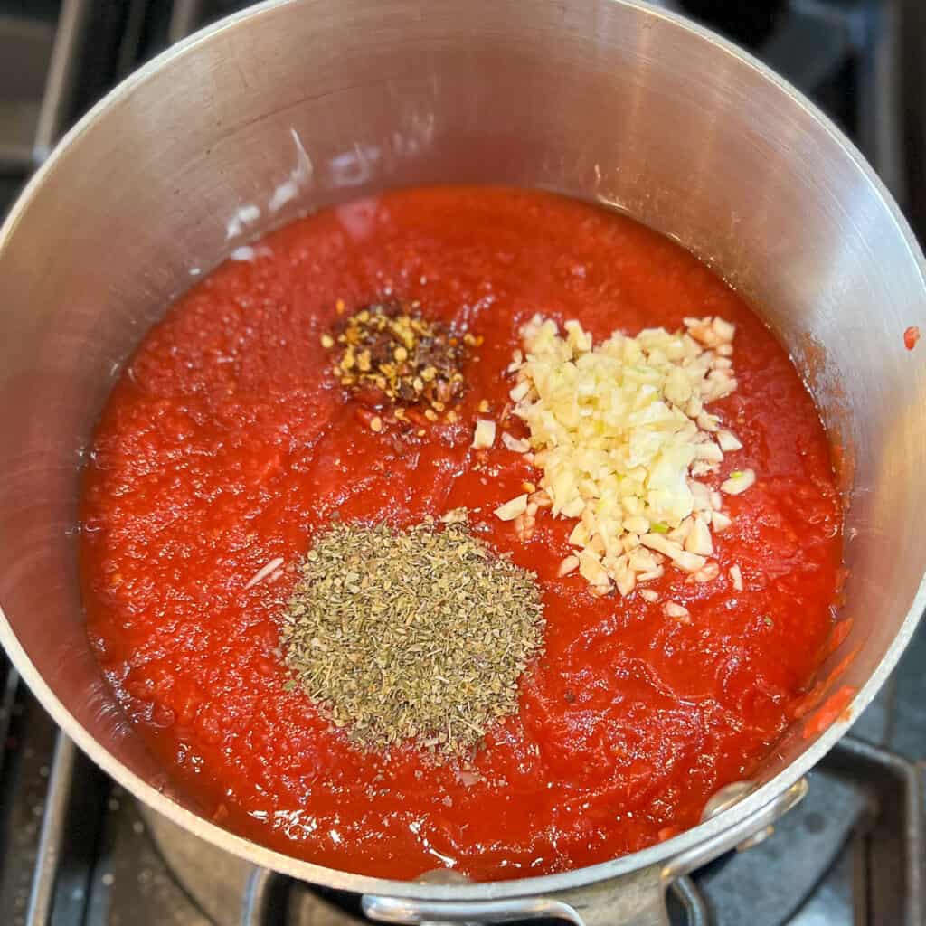 top view of the spaghetti sauce added to the pot on the stove with garlic and seasonings before cooking