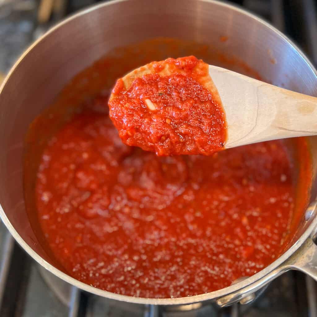 Vegan spaghetti sauce having been stirred with a wooden spoon.