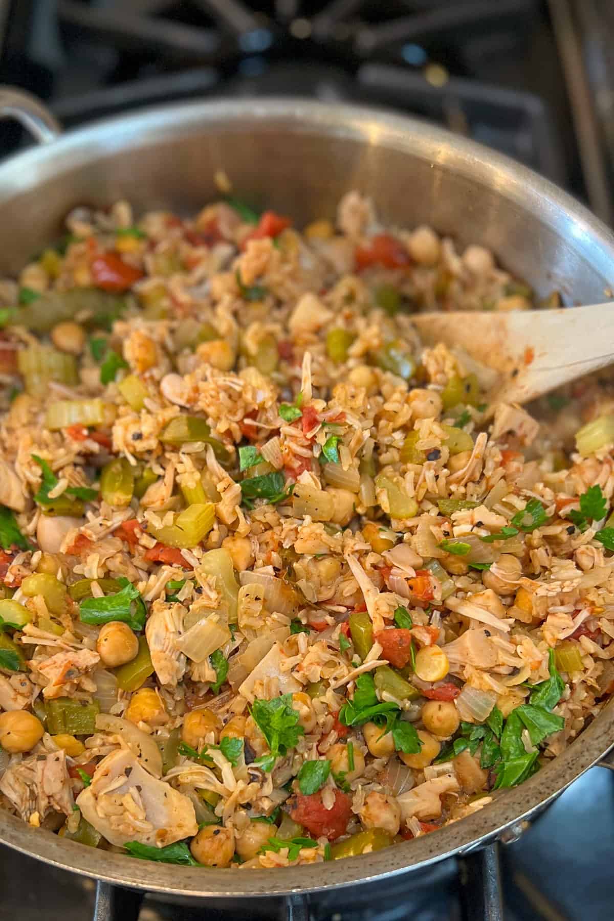 side view of jackfruit jambalaya in a large sauté pan with wooden spoon