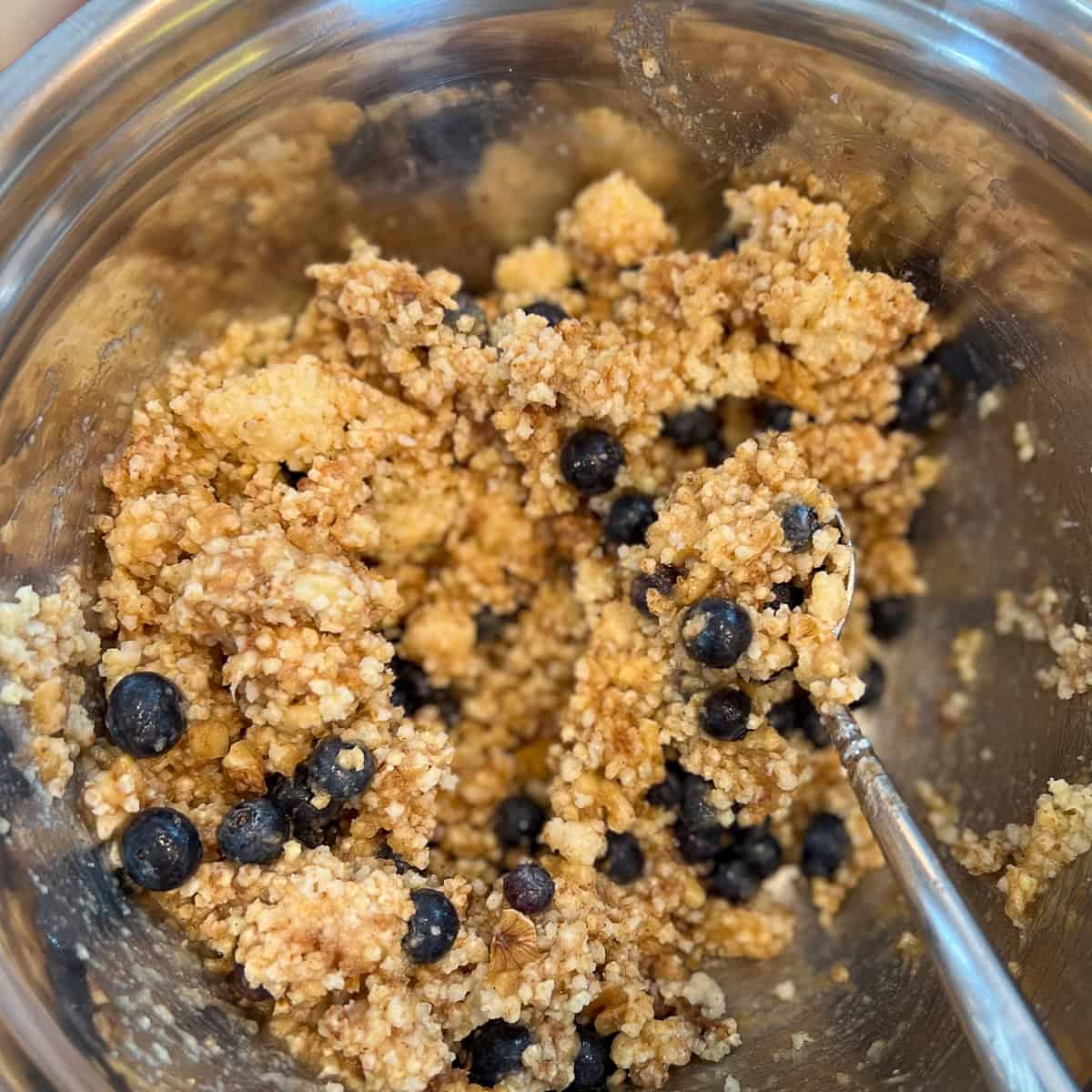 Blueberry millet muffin batter being combined in a mixing bowl.