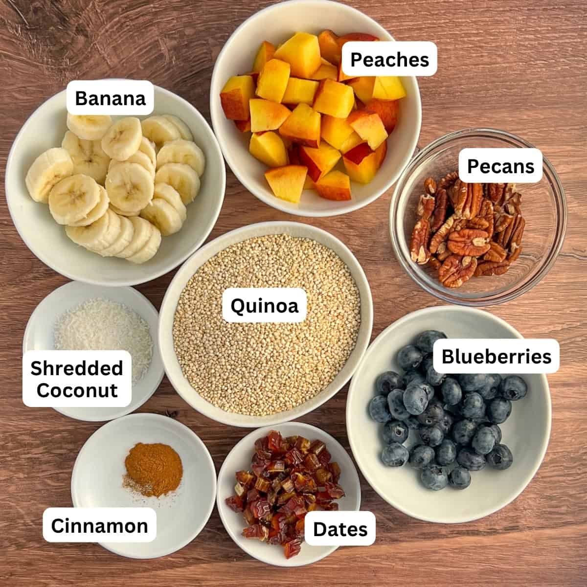 Ingredients for the vegan quinoa breakfast bowl: peaches, banana, pecans, quinoa, shredded coconut, blueberries, dates, cinnamon, cardamom.
