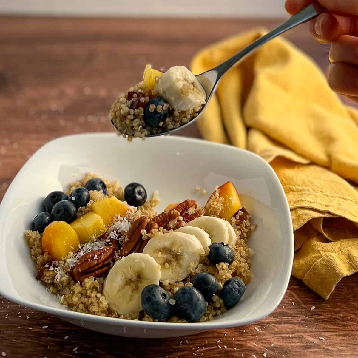 side top view of vegan quinoa power bowl in square white bowl with spoon and napkin on the side