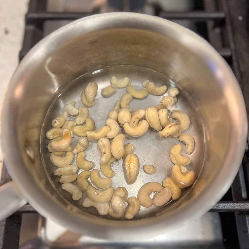 Cashews in a pot of water simmering on the stovetop.