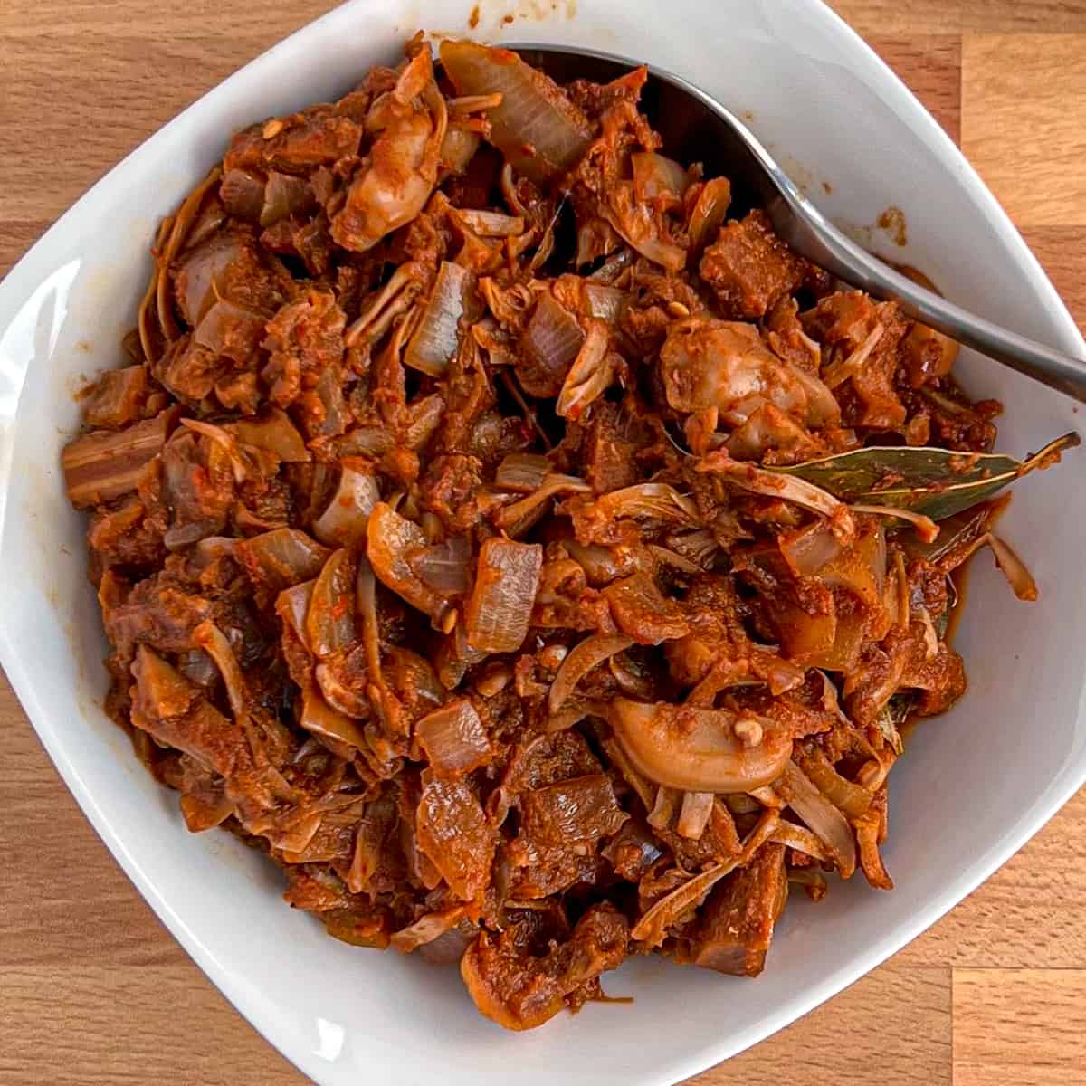 top view close up of vegan jackfruit birria in a white bowl with spoon on the side
