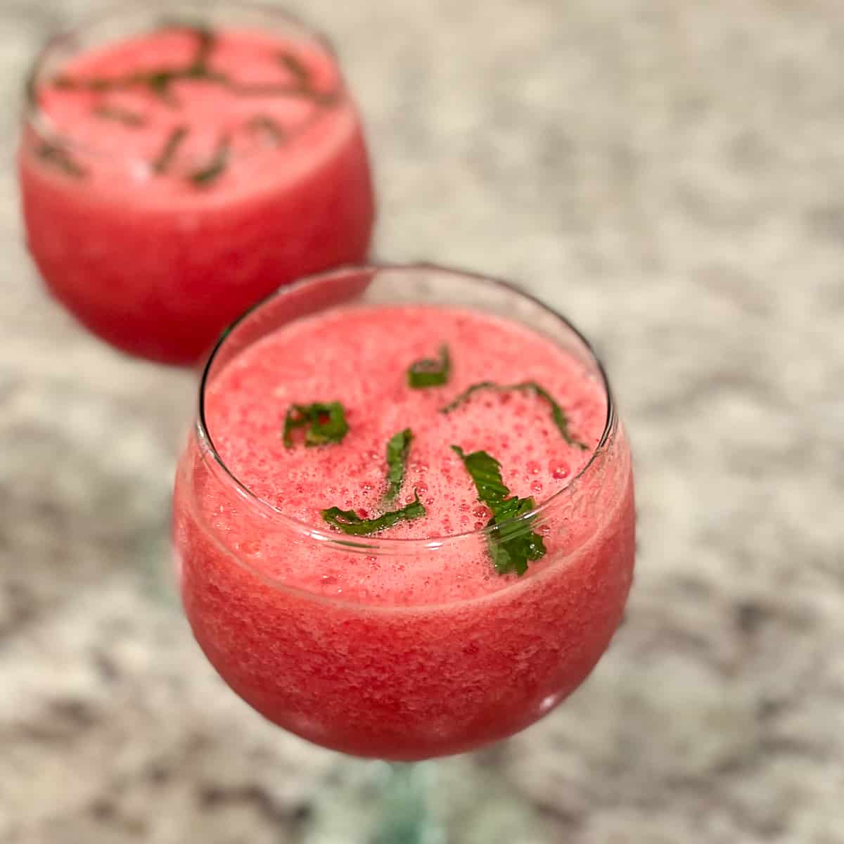 top side view close up of two glasses of frosty watermelon mint mocktails with fresh chopped mint on top