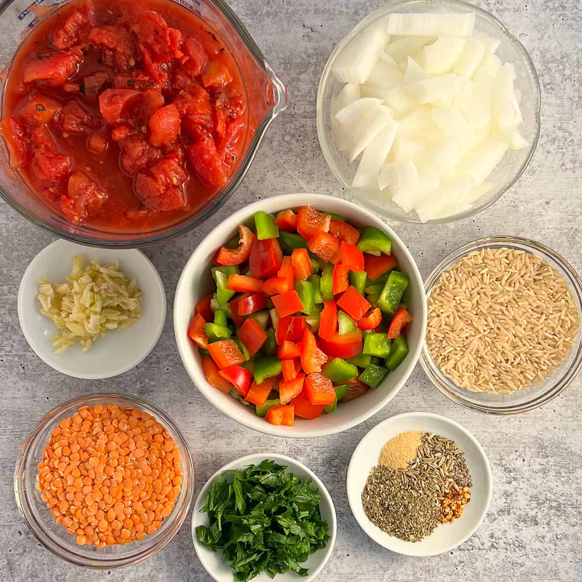 top view of key ingredients: bell pepper, onion, rice, garlic, diced tomatoes, lentils, seasonings, parsley 