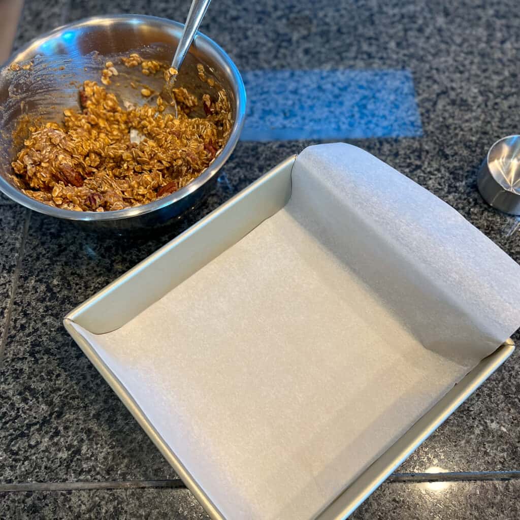 A parchment lined baking pan with the mixture ready to spread into the pan.