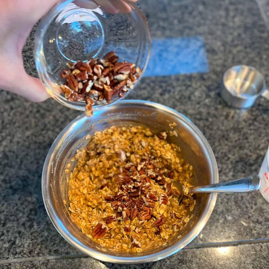 A woman's hand adding ingredients to a mixing bowl.