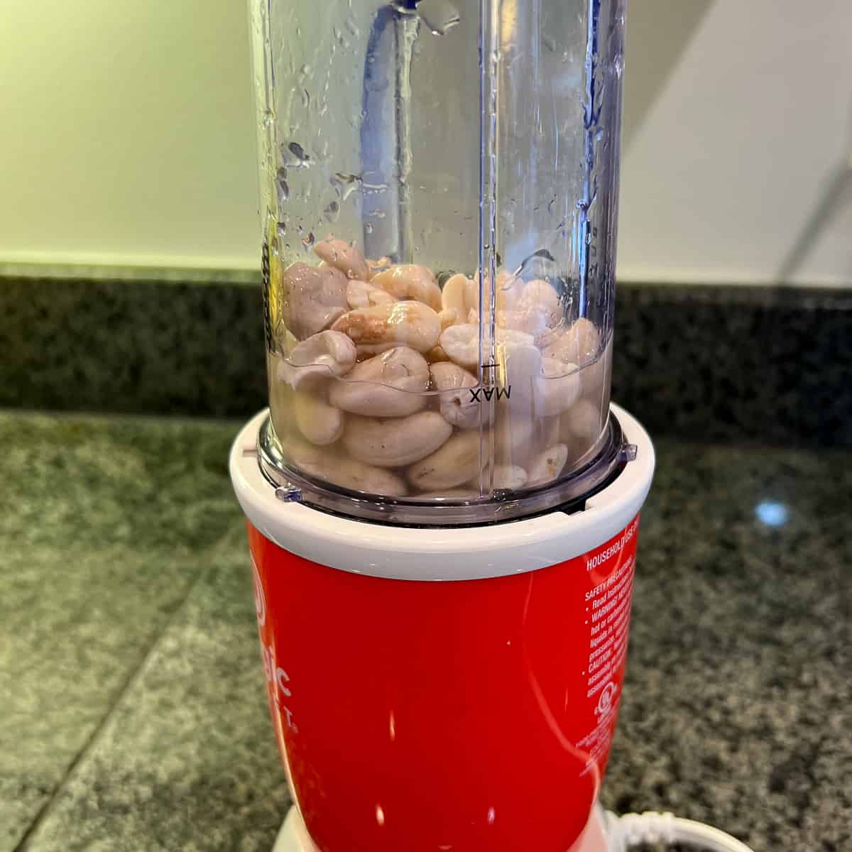 side view of a mini blender with cashews, water, lemon juice and apple cider vinegar