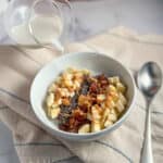 top side view of almond milk being poured into a bowl of oatmeal with fruit and peanut butter