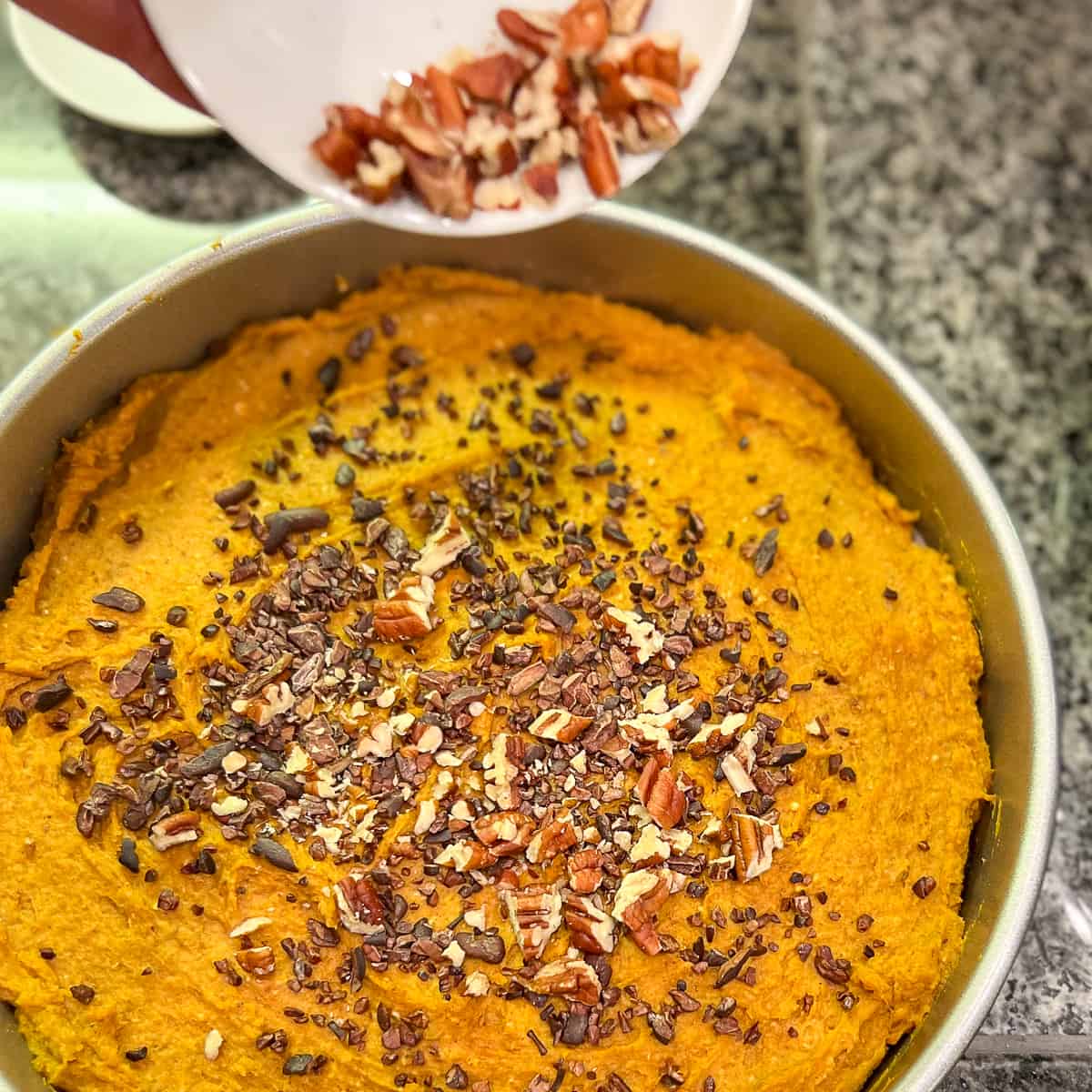 Chopped nuts being added to the crustless vegan sweet potato pie.