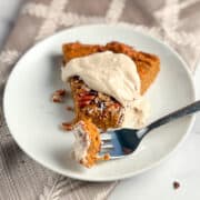 top side view of a slice of pie with cream on top and fork holding a bite