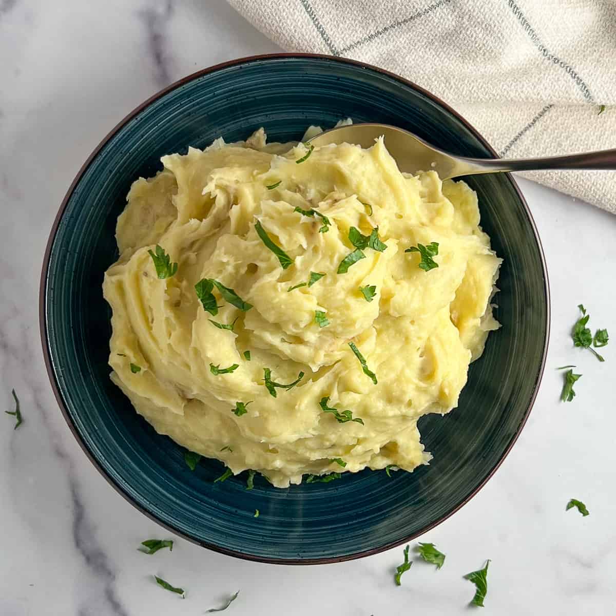 top view of a dark blue bowl with creamy garlic mashed potatoes
