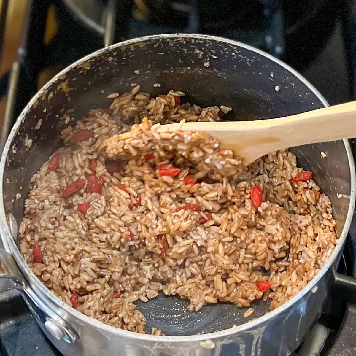 oat with goji berries being stirred with a wooden spoon