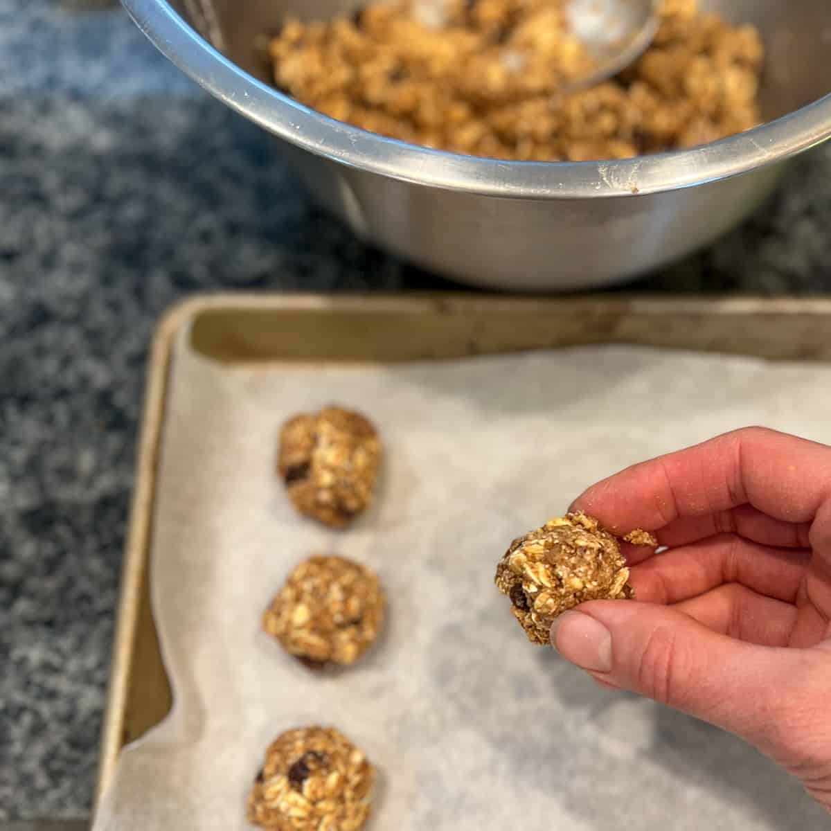 cookie dough being formed into small round balls on a parchment-lined baking sheet