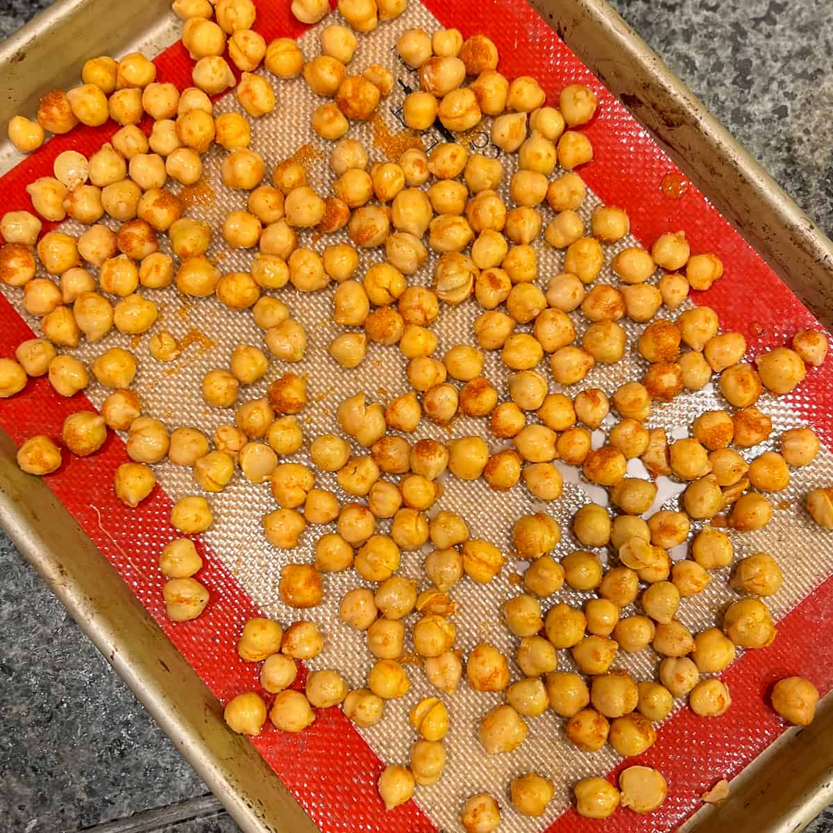 top view of chickpeas spread across a silicone mat lined baking sheet