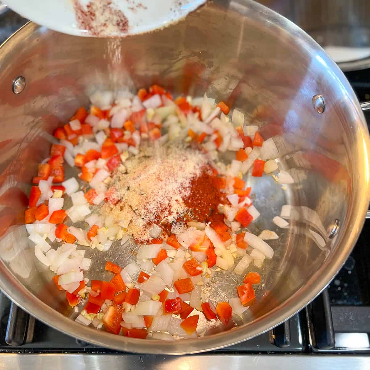 top side view of spices being added to the pot with veggies