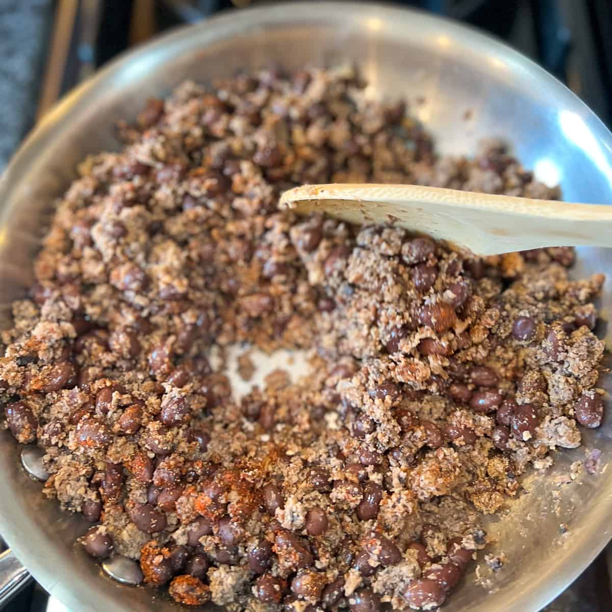 top view of vegan taco meat mixture being stirred with a wooden spoon
