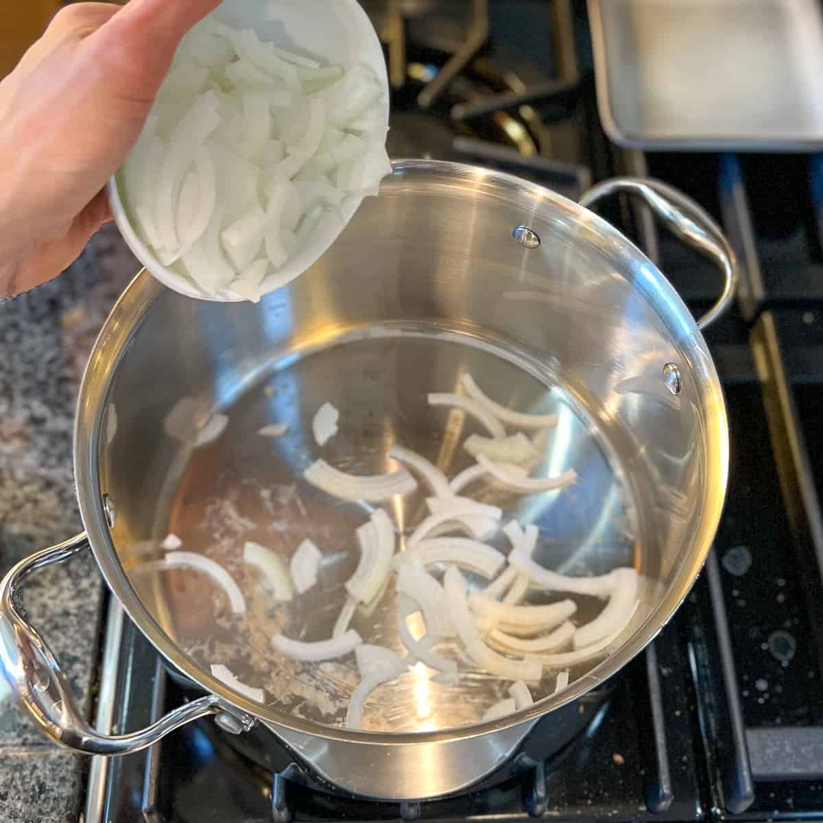 sliced onions being added to a large pot