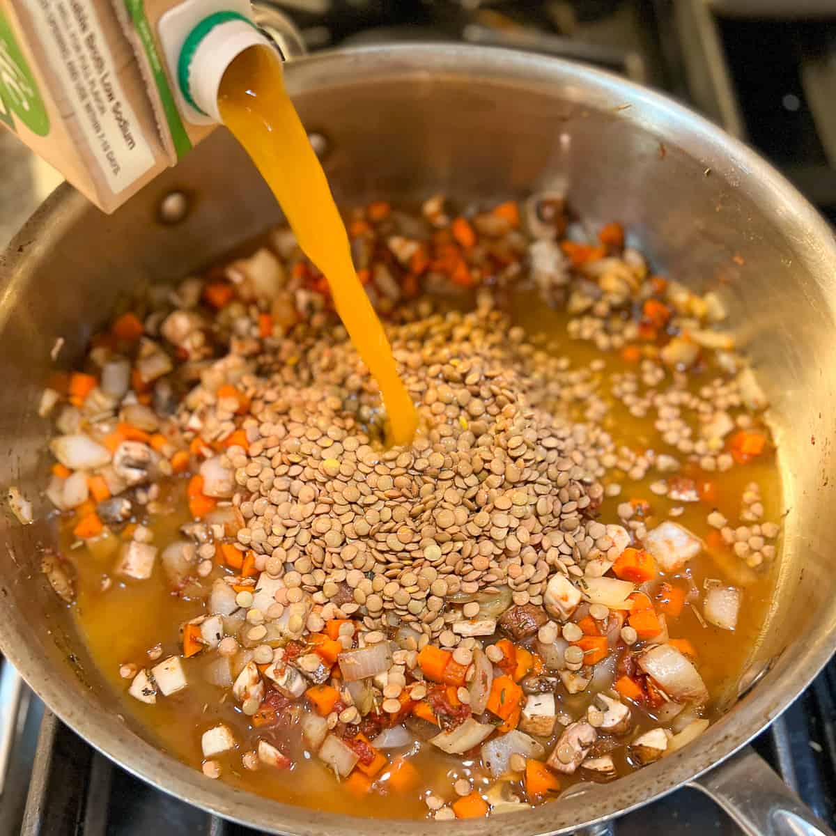 low sodium vegetable broth being added to the pan with lentil and veggie mixture